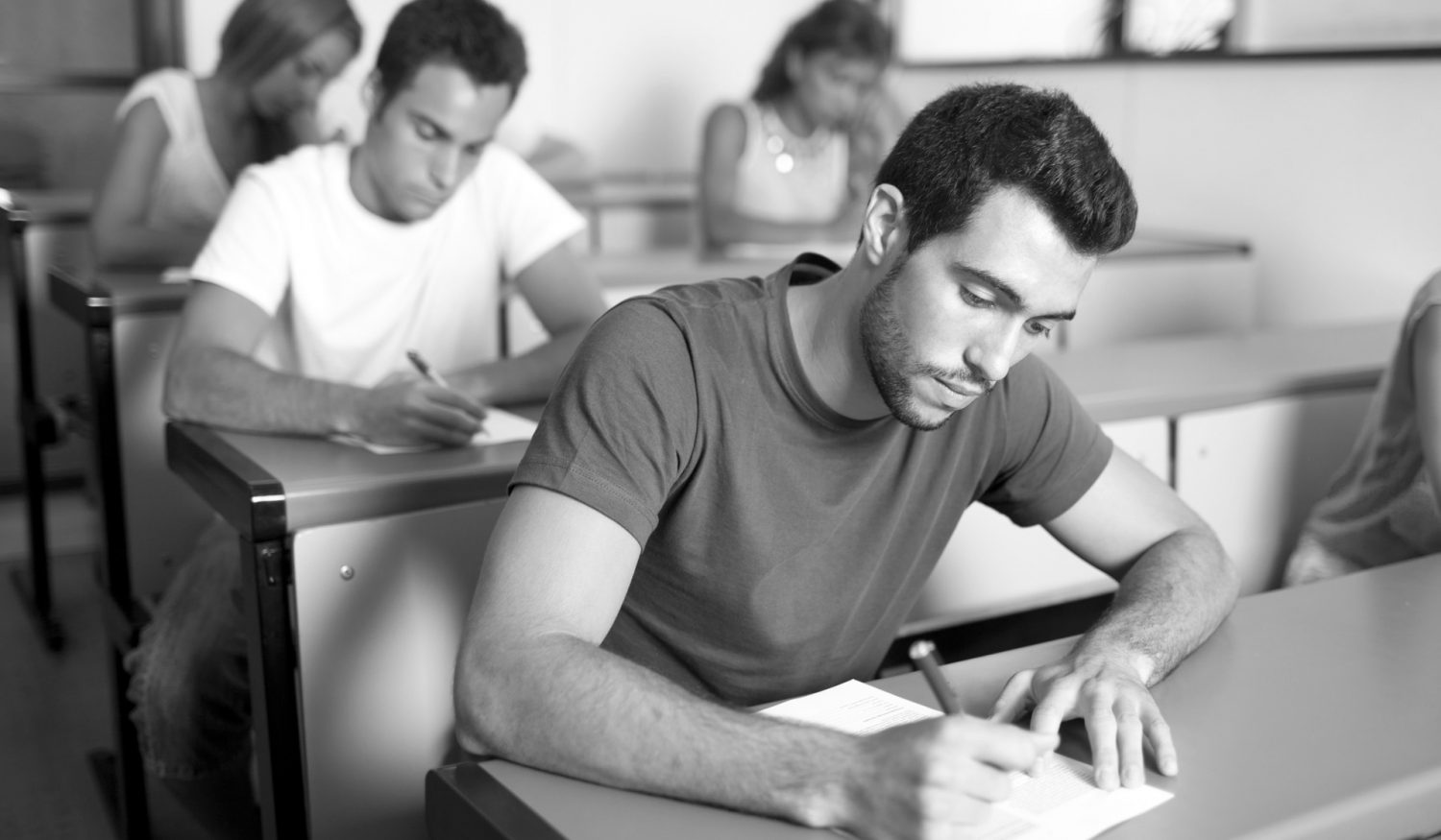 Good-looking male student writing an exam